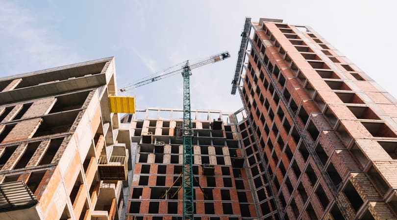 Low-angle view of two high-rise buildings under construction with cranes